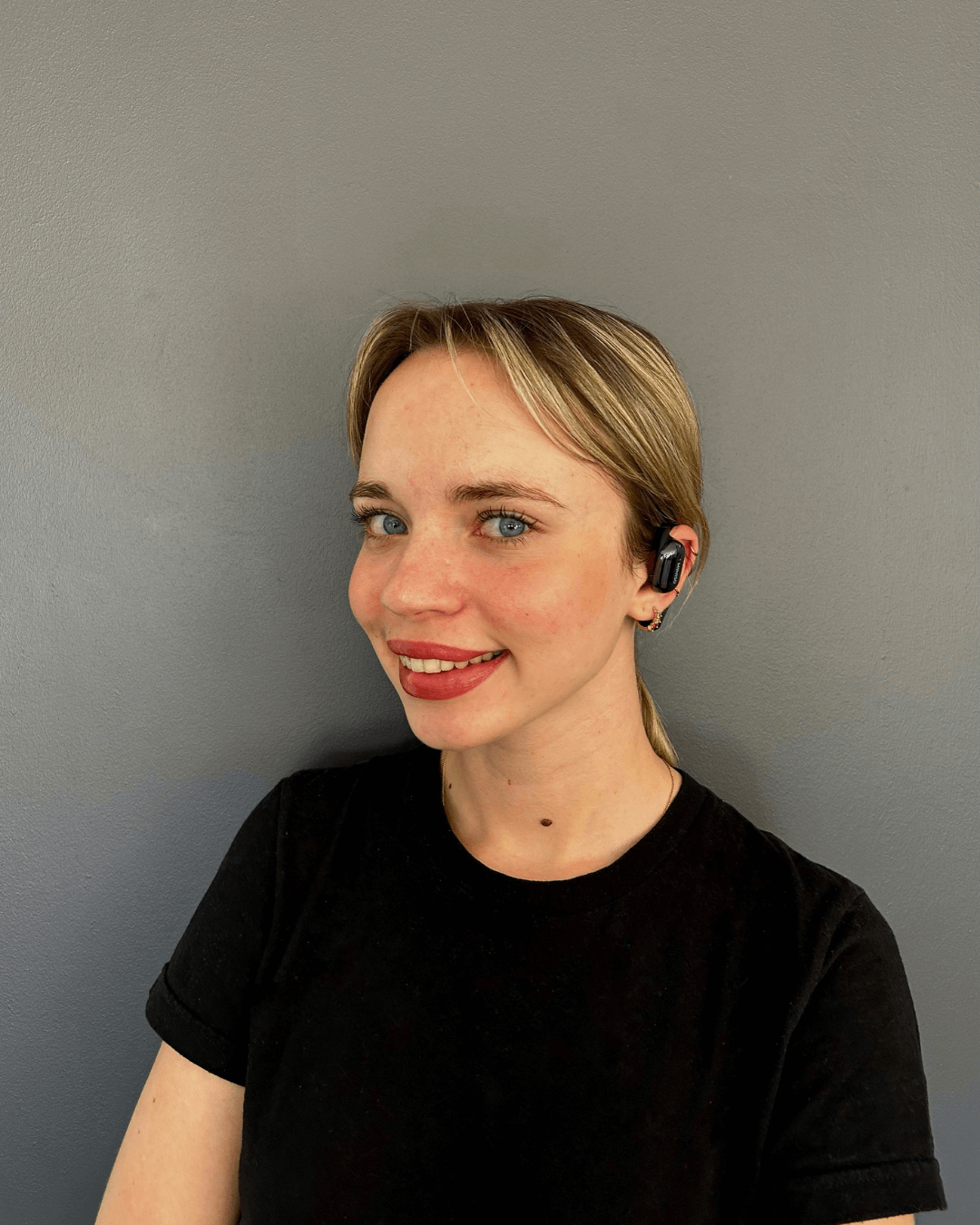 Femme souriante portant les écouteurs traducteurs Hearific, démonstration du port confortable et design élégant
